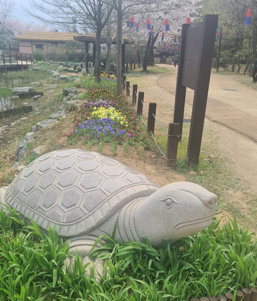 Schildpad beeld met traditionele tuin en lampionnen op de achtergrond